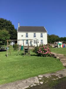 a white house with a playground in the yard at The Farmhouse in Swansea