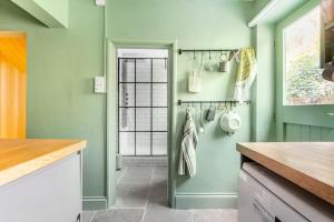 a kitchen with green walls and a window at Rumple Cottage in Wingfield