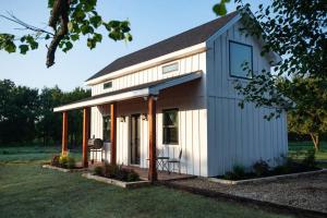 a tiny house with a porch on a lawn at Cowbell Cabin 15min to Downtown Waco in Waco