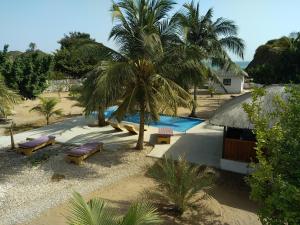 a resort with a palm tree and benches next to a pool at LE 17 to DJIFFER in Palmarin