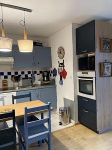 una cocina con armarios azules y una mesa con sillas en Appartement très agréable dans belle résidence, classé 3 étoiles par le comité départementale du tourisme en Haute Garonne, en Luchon