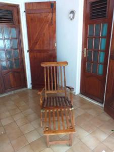 a wooden chair sitting in front of two doors at Maison créole chaleureuse avec stationnement in Le Gosier