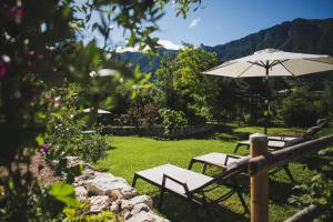a patio with two tables and an umbrella at Coste del Gaggio - Country House B&B - Garda Trentino in Drena