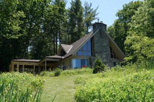 a house with a stone chimney on a field at Black River Cottage in Milford