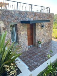 a stone house with a wooden door and a patio at Los Mirlos in La Cumbre