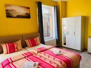 a bedroom with a bed with yellow walls and a window at M&M Hotel - Harburg in Hamburg