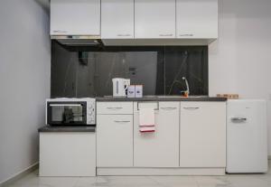 cocina con armarios blancos y microondas en Accommodation in the center of Veria en Veria