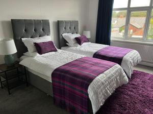 two beds in a bedroom with purple and white sheets at Hidden Gem w/ parking Short walk to Pleasure Beach in Blackpool