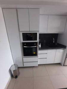 a white kitchen with white cabinets and a microwave at Apartamento ubicado en Bellas Artes in Caracas