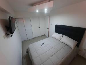 um pequeno quarto com uma cama branca e uma televisão em Apartamento ubicado en Bellas Artes em Caracas