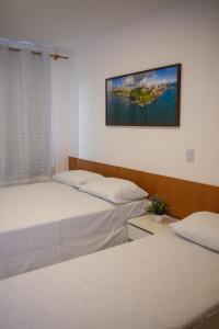 勞魯－迪弗雷塔斯的住宿－POUSADA PEDRA DE JACÓ，一间设有两张床的客房,墙上挂着一张照片