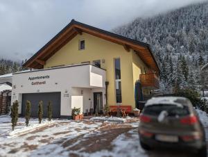 een auto geparkeerd voor een huis in de sneeuw bij Appartements Gotthardt in Flachau