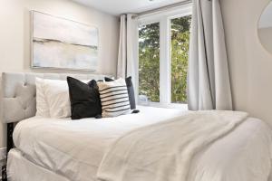 ein Schlafzimmer mit einem weißen Bett mit Kissen und einem Fenster in der Unterkunft Blue Mountain Chalet Condo with Amazing Location in Blue Mountains