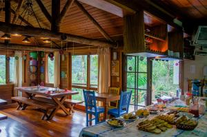 a dining room with a table and chairs and windows at Pousada Rancho Das Framboesas in Visconde De Maua