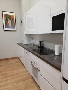 cocina con armarios blancos y encimera negra en Apartamento Retiro, en Madrid