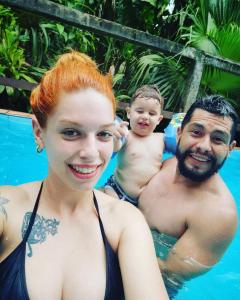 un homme et une femme dans la piscine avec un bébé dans l'établissement Pousada do Oasis, à Morretes