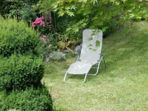 uma cadeira branca sentada na relva no quintal em Apartment Monte Rosa em Delnice