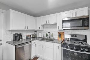 a kitchen with white cabinets and stainless steel appliances at Campbell's Buttercup Shotgun! in Columbus