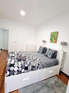 - une chambre blanche dotée d'un grand lit avec des draps noirs et blancs dans l'établissement Anjos Apartment - Ilha do Príncipe, à Lisbonne