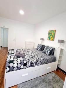 um quarto branco com uma cama grande e lençóis brancos e pretos em Anjos Apartment - Ilha do Príncipe em Lisboa