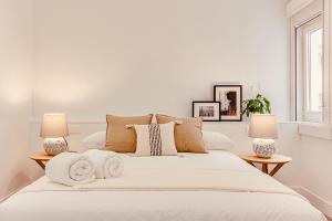 a white bedroom with a large white bed with two lamps at Main Street Deluxe in A Coruña