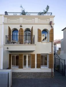 a white building with wooden shutters and a balcony at Molcho Neve Tzedek in Tel Aviv