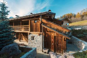 a wooden house with a stone wall at Luxury Cortina in Cortina dʼAmpezzo