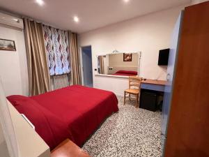 a bedroom with a red bed and a desk and a mirror at Hotel Saratoga in Vigevano