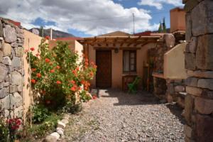 a small house with a stone wall and a door at Cabañas La rueda in Tilcara
