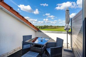 Un balcón con una mesa y sillas y una sombrilla. en Villa Moorstern am Badesee Tannenhausen, en Aurich