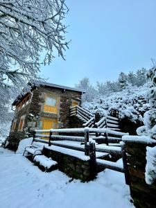 une maison dans la neige avec un banc dans l'établissement Aldea Couso Rural, à Sarreaus