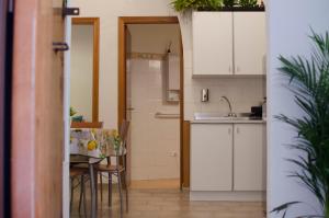 uma cozinha com armários brancos e uma mesa com cadeiras em La Casetta em Catânia