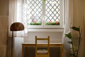 una mesa con una silla y una ventana con flores en La Casetta, en Catania