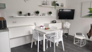 TV y cocina con mesa y sillas blancas. en FeWo ALBTALECK - Wohnen im Kurort Waldbronn, en Waldbronn
