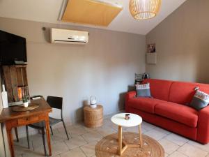 a living room with a red couch and a table at La Maisonnette de vacances avec piscine privée pour 2 pers in Lorgues