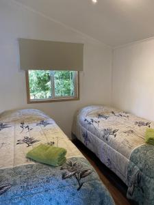 1 dormitorio con 2 camas y ventana en Cabañas Mahuida, en Villarrica