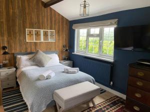 Dormitorio azul con cama y ventana en Couples Getaway, with Mountain Views/Dog Friendly en Crickhowell