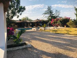 a driveway of a house with a pool and flowers at Lodge Kabacoto in Nioro du Rip