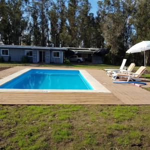 una piscina con terrazza e due sedie e ombrellone di Piedra De Agua Chacra, casa, piscina, bosque, río. a Minas
