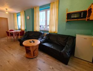 a living room with a black leather couch and a table at Pizzeria Pension Damiano in Muldenhammer