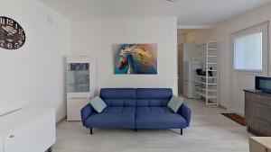 een woonkamer met een blauwe bank en een schilderij van een paard bij Gîte « l’Escapade Cabassoise » in Cabasse