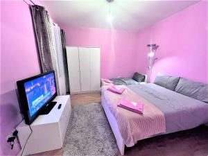 a pink bedroom with a bed and a flat screen tv at Spacious 1 Bedroom Flat in High Wycombe