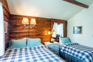 two beds in a room with wooden walls at Log Cabin Motel in Pinedale