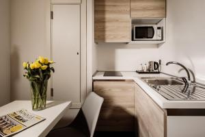 a kitchen with a vase of yellow flowers on a table at be.HOTEL in St. Julianʼs