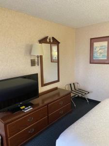 a hotel room with a bed and a dresser with a television at AmeriCoast Inn in Brookings