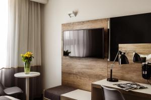 a hotel room with a desk and a television on a wall at be.HOTEL in St. Julianʼs