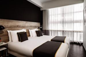 a hotel room with two beds and a window at be.HOTEL in St. Julianʼs