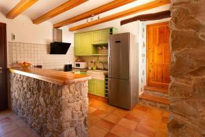 cocina con armarios verdes y nevera de acero inoxidable en Rural ca´s Pelut, en Tàrbena