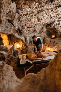 a man getting a woman laying on a bed in a cave at Pensiunea Casa Zanelor in Floreşti