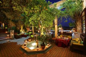 un patio al aire libre con una bañera de hidromasaje con árboles y mesas en Riad Arabesque & Spa, en Fez